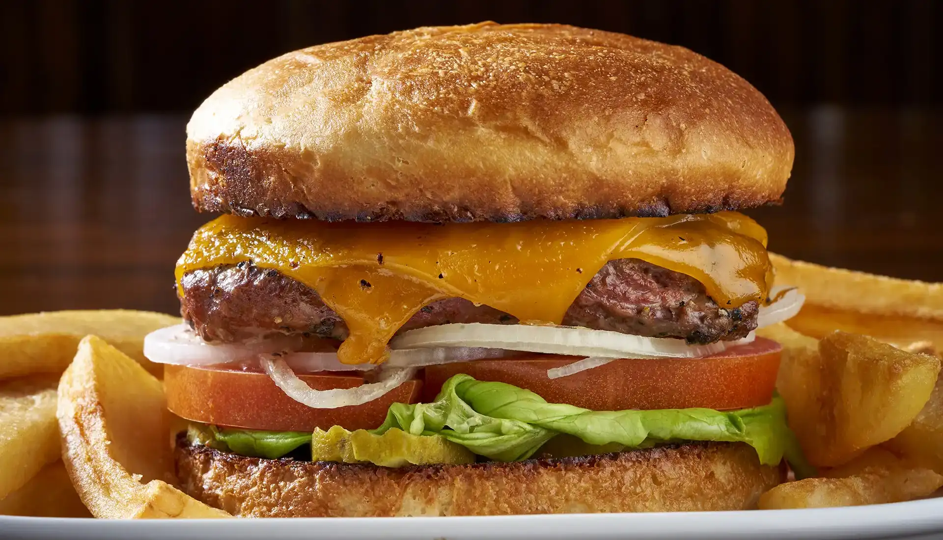 We top our Angus burger with Cheddar cheese, pickles, onions, tomatoes and Boston Bibb lettuce on a homemade bun.