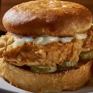 A lightly breaded chicken breast deep fried and served on a freshly toasted bun with pickles.